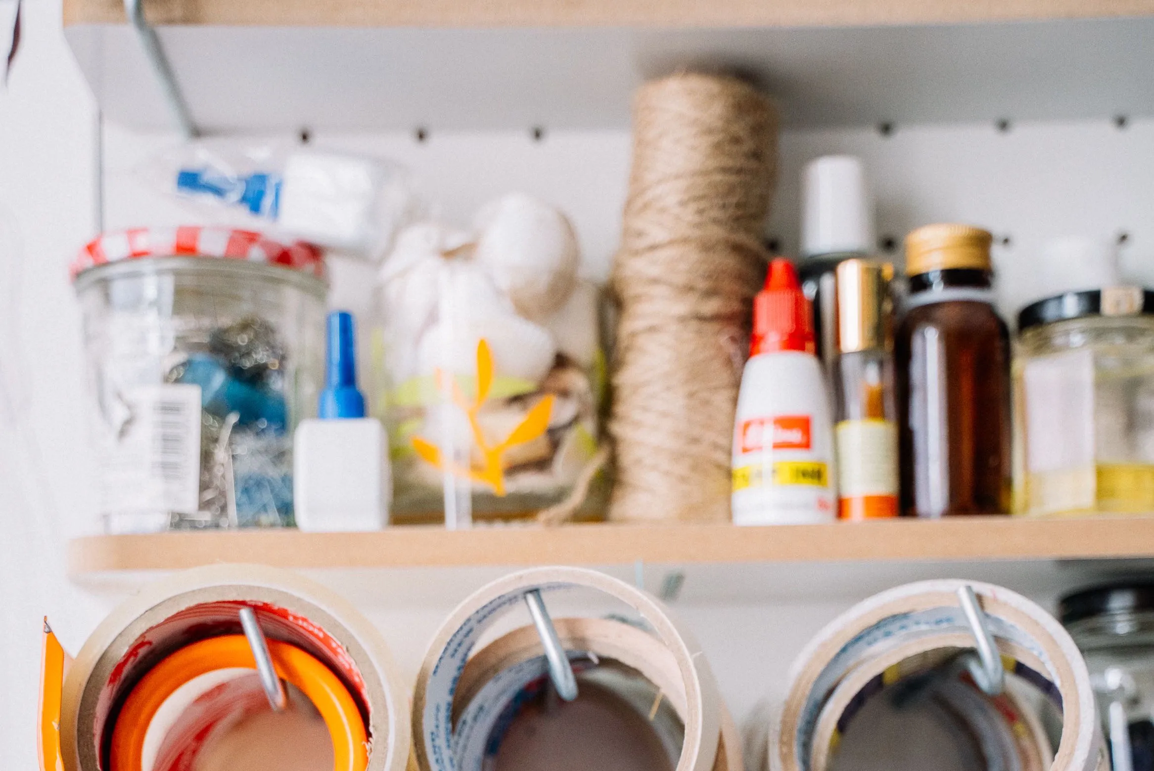 Shelves of crafts supplies like glue, tape, and string